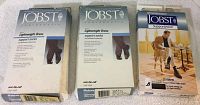 Front view of three original JOBST sock boxes showing two Lightweight Dress over-the-calf socks and one men's high support knee-high sock