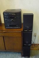 Full view of the stacked SHARP CMS-R500AV stereo system with two speakers on wood furniture, showing general setup and condition.