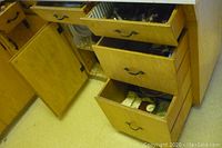 Wooden kitchen cabinets and drawers open showing contents inside, including various kitchen items