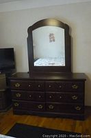 Full view of dark wood dresser with large arched mirror reflecting part of room