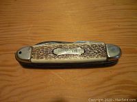 View of closed vintage folding knife showing textured handle and metal plaque labeled 'CAMPERS KNIFE'