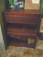 Front view of the wood storage cabinet showing the two rolling doors and open shelf.