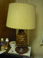 Front view of table lamp showing ribbed brown base and beige stitched fabric shade.