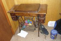 Full view of the oak cabinet with cast iron treadle base and storage drawers, showing overall condition and color.
