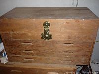 Closed wooden tool chest with visible wear and metal latch on the front.