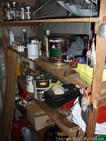 Wooden shelving filled with various household supplies including paint cans, maintenance liquids, and containers like mason jars