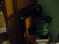 Overview photo showing wooden chairs stacked near the vacuum, with black hose coiled on top and metal holder visible
