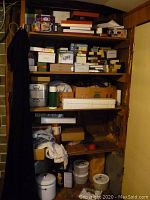 View of shelving with numerous boxed and assorted storage items including shoeboxes and metal tins.