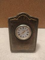 Front view of vintage sterling silver clock frame with inset circular clock and Roman numeral dial.