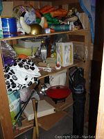 Full view of wooden shelving unit with various items on each shelf, including Viking-style helmet with horns, bowls, gloves, and kitchen utensils.