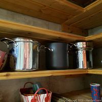 Stainless steel and non-stick pots and pans on wooden shelf