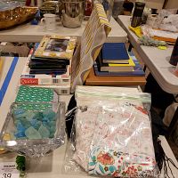 Top view showing stacked photo albums, frames, seaglass in crystal bowl, floral-patterned textiles in plastic bag