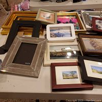 Tabletop display of various framed art and empty frames showing different styles and colors.