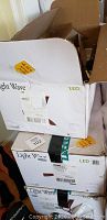 Photo showing three stacked boxes labeled Light Wave LED with yellow price stickers and shipping labels