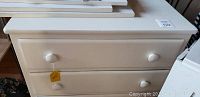 Small painted wooden dresser with two drawers and round knobs, showing the front view.