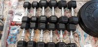 Hex dumbbells arranged in rows with accessories and small parts for assembly