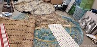 Various throw rugs and carpets stacked and spread on ground, showing different colors and patterns