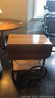 Overall photo showing the wood folding top tea trolley with its rectangular surface, large wooden wheels, and lower shelf.