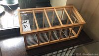 Photo of the mini greenhouse showing wooden frame and glass top with slatted wooden sections beneath.
