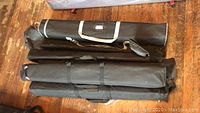Four black canvas carry bags lying on a wooden floor, containing pop up banners and stands.