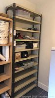 Full view of the ten shelf metal shelving unit partially filled with containers and other items, showing its size relative to nearby furniture.