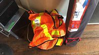 Pile of orange safety vests with yellow reflective stripes piled on the floor