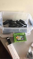 Plastic bin with eleven black Garmin walkie talkies inside, selfie stick in box and Garmin Nuvi 58 LM GPS in green box in foreground