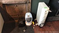 Three plug-in electric heaters shown together including an oscillating tower heater, oil-filled radiator heater, and a black Super Furnace heater.