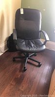 Front view of black vinyl desk chair with casters and arms showing padded seat and backrest.