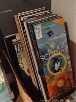 Photo showing a stack of about 30 mounted posters leaning against a wall, some graphics with text visible on the top poster.
