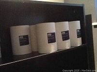 Seven large white York commercial paper rolls arranged on shelf.