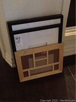 Five frames grouped together; four black frames with mounted images and one light wood multi-photo frame without pictures.