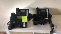 Nine black TalkSwitch TS-350i IP phones arranged with handsets and cords visible, all on a flat surface.
