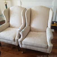 Photo showing both beige floral patterned Ethan Allen armchairs side by side, wingback style with wooden legs.
