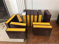 Overall view of 10 brown hardcover magazine binders with yellow page edges, containing National Geographic magazines.