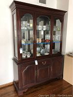 Full frontal photo of Ethan Allen wooden hutch buffet with glass doors, displaying glass shelves and wood cabinets below.