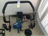 Fitness equipment including ab roller with padded knee rest and handles, dumbbells, push-up bars, massage roller, and balance pad.