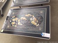 Top view of the rectangular coffee table showing black surface with mother of pearl floral designs and intricate border patterns.