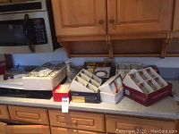 Multiple boxed sets of glassware and china on kitchen counter showing the quantity and packaged condition