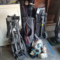 Overview photo showing the golf bags, carts, bags of golf balls, and accessories on the floor in a garage setting.
