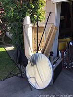 Photo showing three black adjustable photography stands with tripods, a round reflector with metallic surface, backdrops, sandbags for weights, and a hard carrying case.
