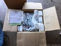 Top-down photo showing the Harman Kardon receiver packed inside the box with styrofoam, cables, and manuals on top.