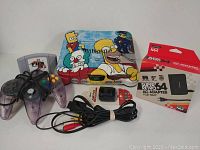 Full view of painted Nintendo 64 console with controllers, game cartridge, AV cables, power adapter box, and memory card arranged for display