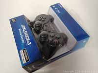 Front view of packaged Sony DualShock 3 wireless PlayStation 3 controller showing branding and controller shape.