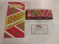 Hoverboard replica displayed alongside original box and certificate of authenticity on flat surface.