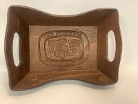 Top view of rectangular wooden basket showing handles and carved farmer scene in the base.