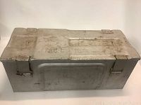Full view of the WWII metal ammo box showing rectangular shape, hinged lid, and latch clamps.