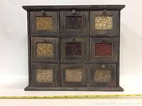 Front view of nine-drawer spice cabinet with visible spices through glass fronts.