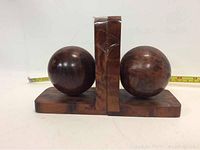 Pair of wooden orb bookends showing front view with large orbs and vertical supports mounted on a wooden base.