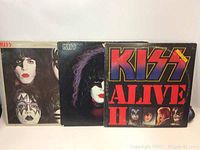 Three KISS vinyl albums showing front covers including 'Alive II' and two with band members' face paint art.